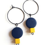 colorful dark blue and yellow wooden beads hanging on a black creole by Pop-a-porter