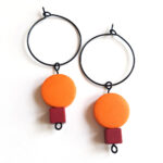 colorful orange and red wooden beads hanging on a black creole by Pop-a-porter.