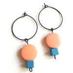 colorful peach and blue wooden beads hanging on a black creole by Pop-a-porter