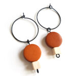 colorful brown and withe wooden beads hanging on a black creole by Pop-a-porter