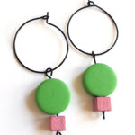 colorful green and pink wooden beads hanging on a black creole by Pop-a-porter
