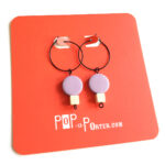 colorful lilac and white wooden beads hanging on a black creole by Pop-a-porter